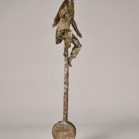 Alt text: Bronze sculpture of a circus performer riding a tall unicycle