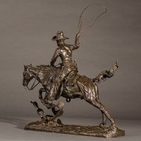 Alt text: Bronze sculpture of a cowboy with a lasso riding a horse jumping over a cactus, side view