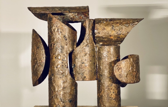 Alt text: Abstract bronze and steel assemblage mounted on a stone block, rear view