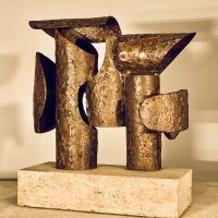 Alt text: Abstract bronze and steel assemblage mounted on a stone block, angled view