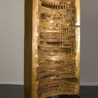 Alt text: Wide, vertical bronze column with concave center and abstracted incised pattern, angled view