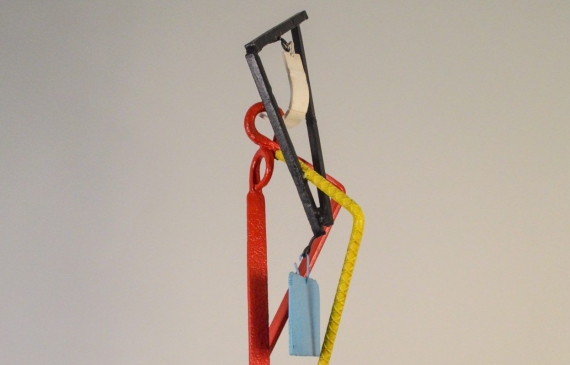 Alt text: Abstract kinetic sculpture of painted welded steel with three hanging/movable pieces, frontal view