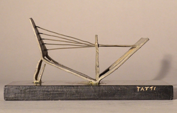 Alt text: Abstract soldered lead sculpture atop a wooden base resembling a drawbridge, side view