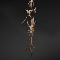 Alt text: Welded abstract iron sculpture on block base, side view