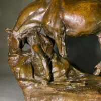 Alt text: Bronze sculpture of a horse bending down alongside a girl sitting near to the ground, peering over a cliff