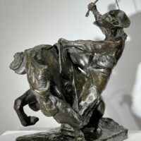 Alt text: Bronze sculpture of a man on a horse with a whip in his hand