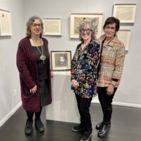 Alt text: 3 women posed with artist portrait