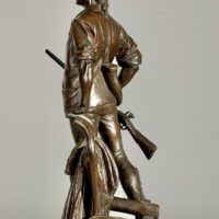 Alt text: bronze sculpture of a man with a gun