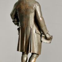 Alt text: Bronze sculpture of man holding a scroll, detail