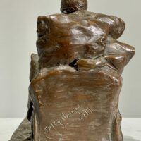 Alt text: Bronze sculpture of a seated man, detail