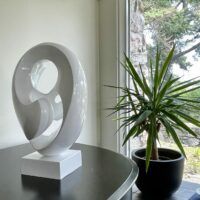 Alt text: glossy, oval shaped sculpture next to a plant