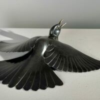Alt text: Bronze sculpture of a bird with wings spread