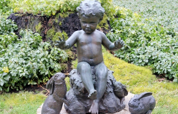 Alt text: Bronze outdoor sculpture of a child with two rabbits