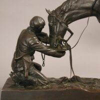 Alt text: Bronze sculpture of a figure kneeling in front of a horse, detail